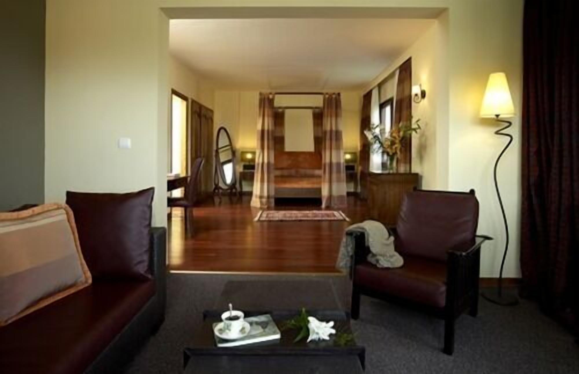 A hotel room with a bed, a sofa, a chair, a coffee table, and a lamp.