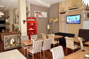 A hotel lobby with a wooden reception desk, striped upholstered chairs, a red telephone booth, and a television on the wall. - Galata Palace Hotel (Istanbul)