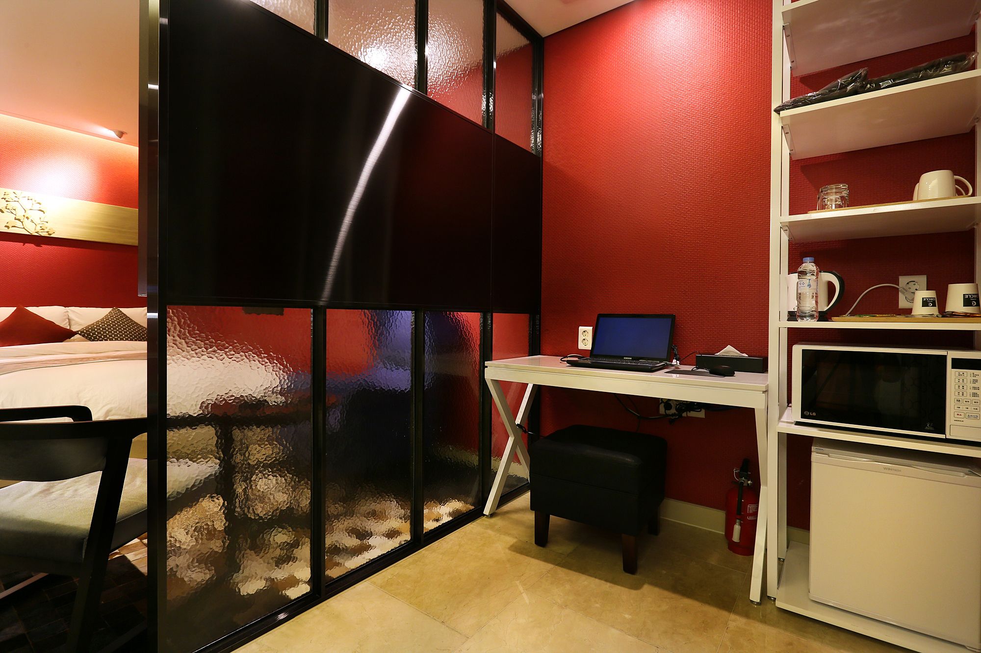 Une chambre d’hôtel compacte comprenant un lit, un bureau avec un ordinateur portable, un four à micro-ondes et un petit réfrigérateur.