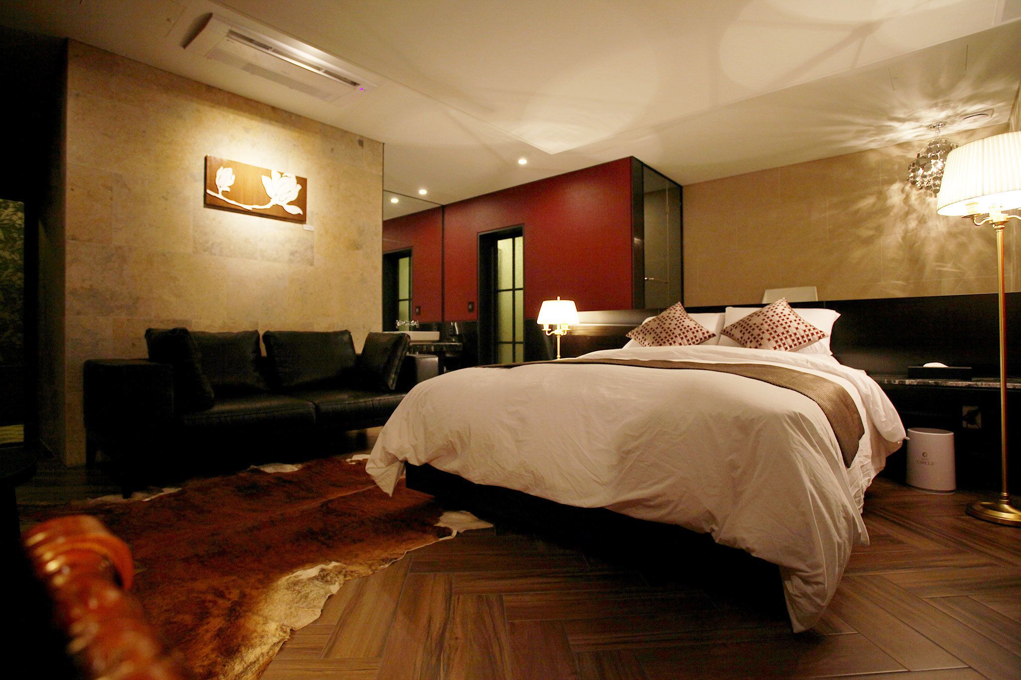 Una habitación de hotel con una cama grande, un sofá de cuero, una alfombra y una obra de arte colgada en la pared.