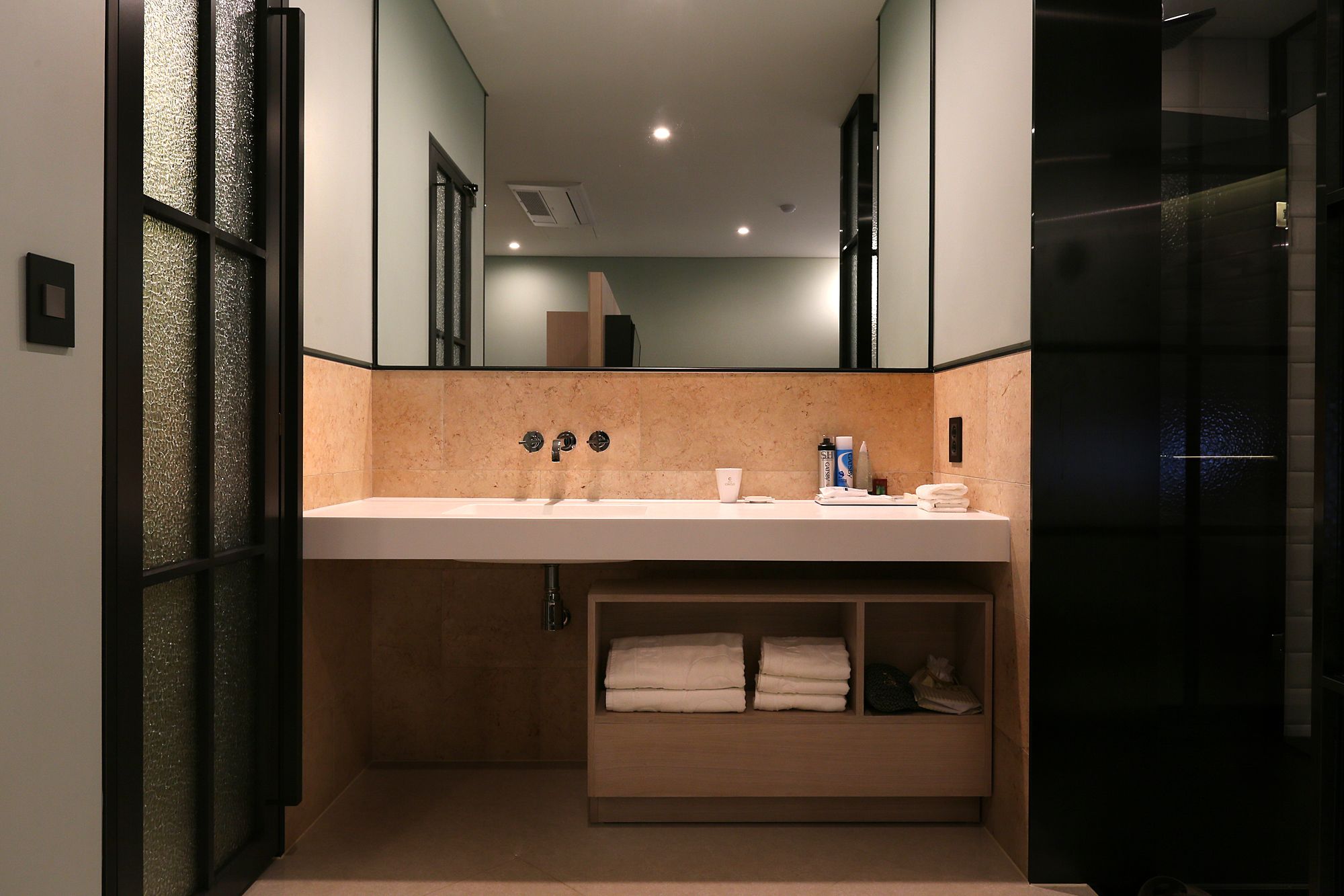 A modern bathroom with a large mirror, a white sink, and a towel rack.