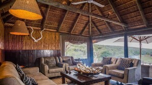 Un rincón acogedor con techo de paja, asientos cómodos y un amplio ventanal con vistas panorámicas.