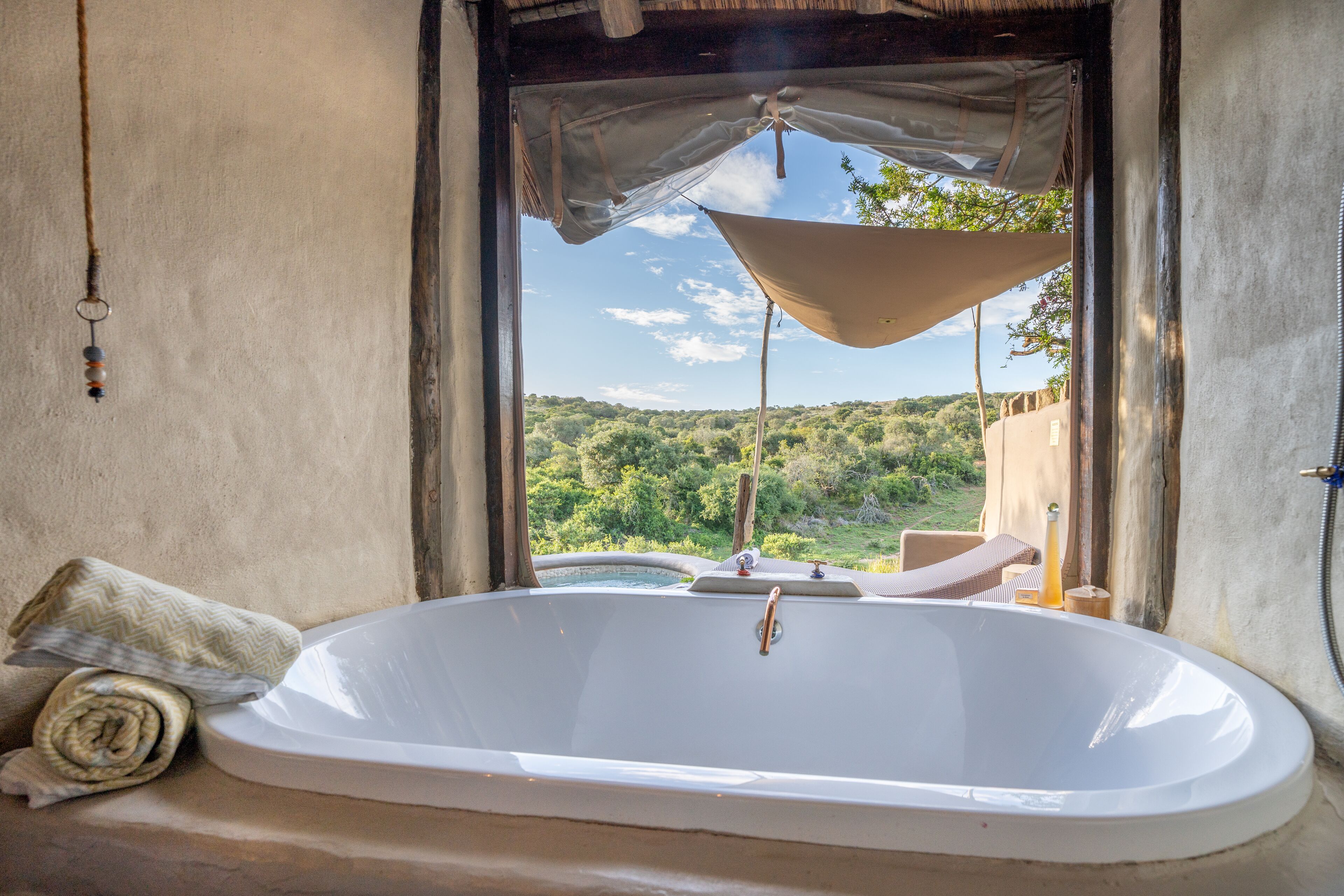 Une grande baignoire dans une pièce au décor rustique, offrant une vue sur un paysage luxuriant.