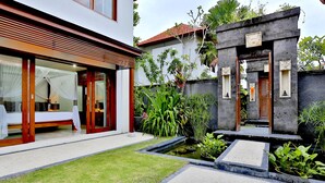 Una casa moderna con un jardín cuidado, un estanque pequeño y una terraza de madera.
