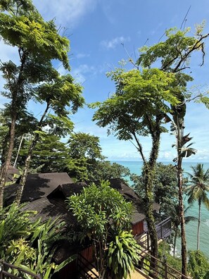 A tropical resort with a wooden structure, lush greenery, and a view of the ocean.