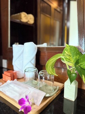A tray with toiletries, a plant, and towels on a wooden surface.