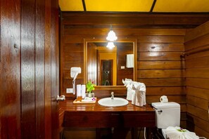 A wooden cabin-style bathroom with a wooden vanity, a sink, a toilet, and a mirror. - Baan Krating Khao Lak Resort (Takua Pa)