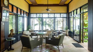 A spacious indoor area with wicker furniture, large windows, and a ceiling fan. - Baan Krating Khao Lak Resort (Takua Pa)