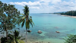 A coastal view with clear turquoise waters, rocky shoreline, and palm trees. - Baan Krating Khao Lak Resort (Takua Pa)