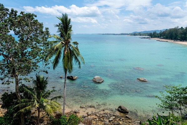 A coastal view with clear turquoise waters, rocky shoreline, and palm trees. - Baan Krating Khao Lak Resort (Takua Pa)