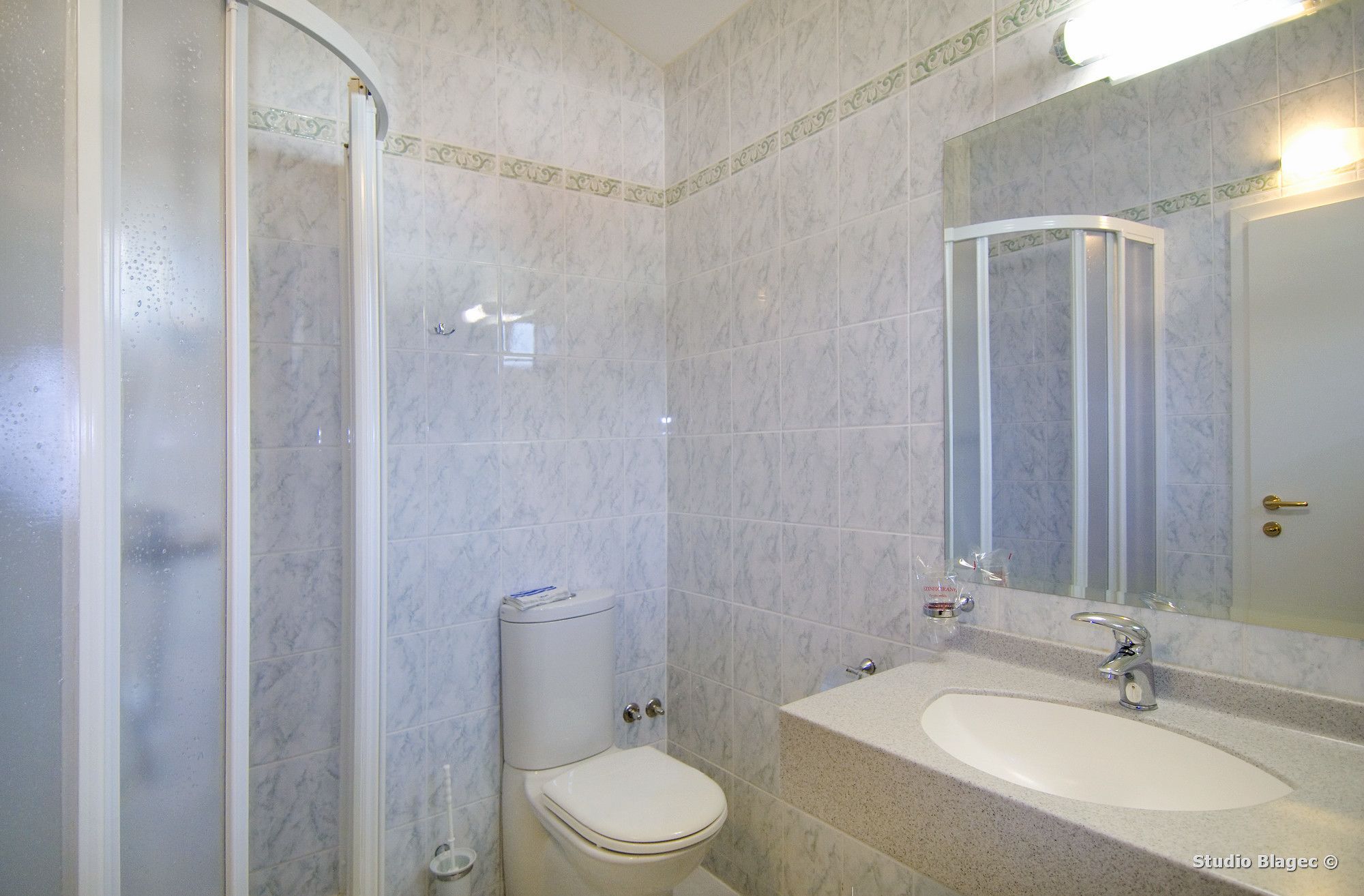 A bathroom with a toilet, sink, and mirror.