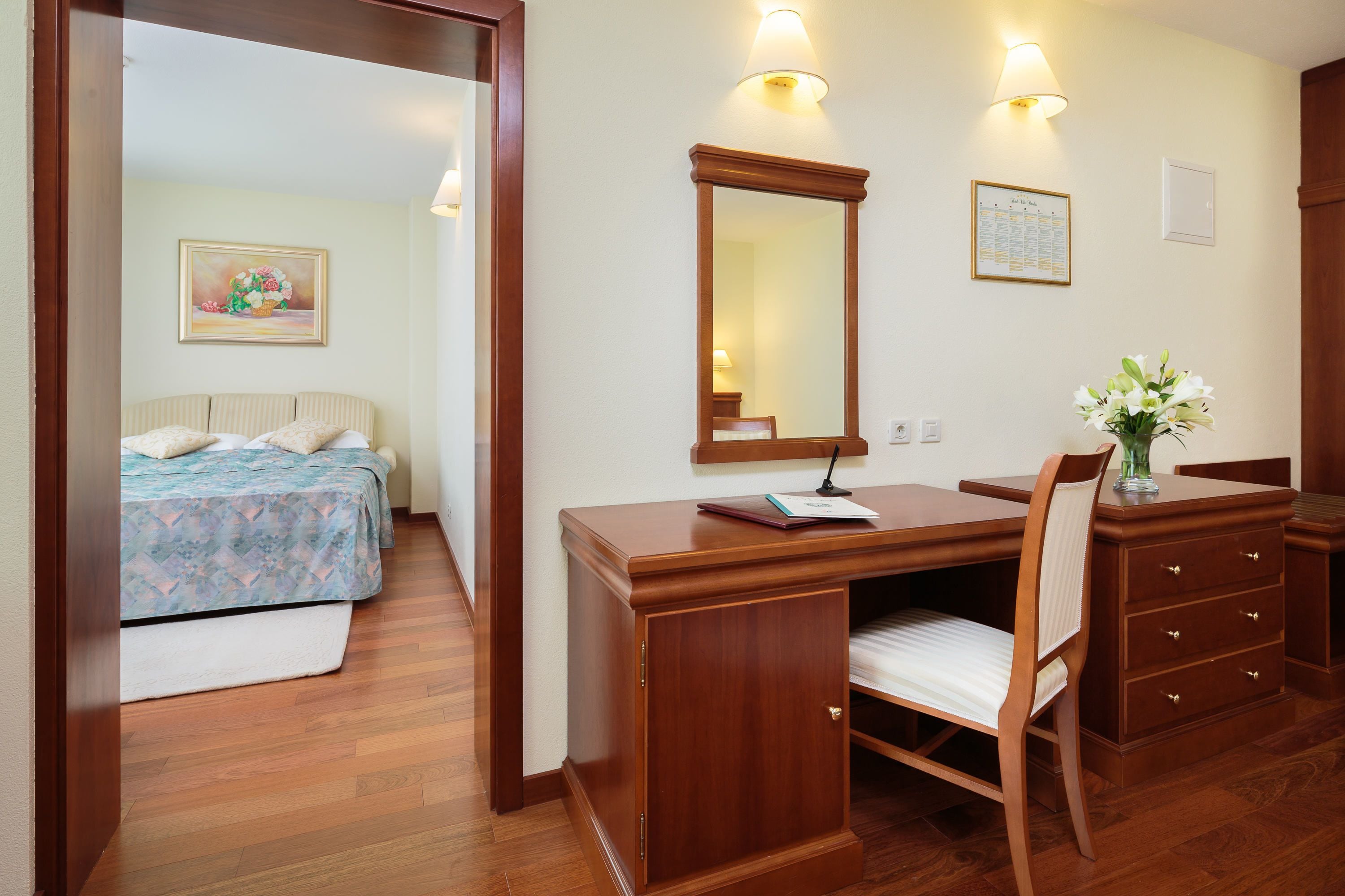 A bedroom with a bed, a desk with a chair, and a dresser.