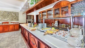 A buffet area with a marble countertop, wooden cabinets, and a variety of food and drink options. - Hotel Bacchus (Baska Voda)
