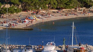 A coastal building with multiple balconies, a marina with boats, and a beach area. - Hotel Bacchus (Baska Voda)