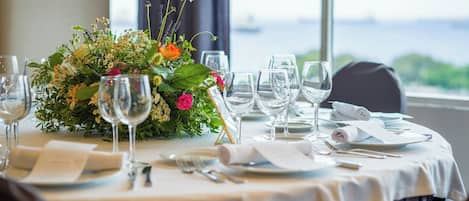 A table set for dining with a floral centerpiece, clear glassware, and a view of the outdoors.