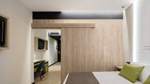 Een hotelkamer met een bed, een bureau, een stoel en een televisie.