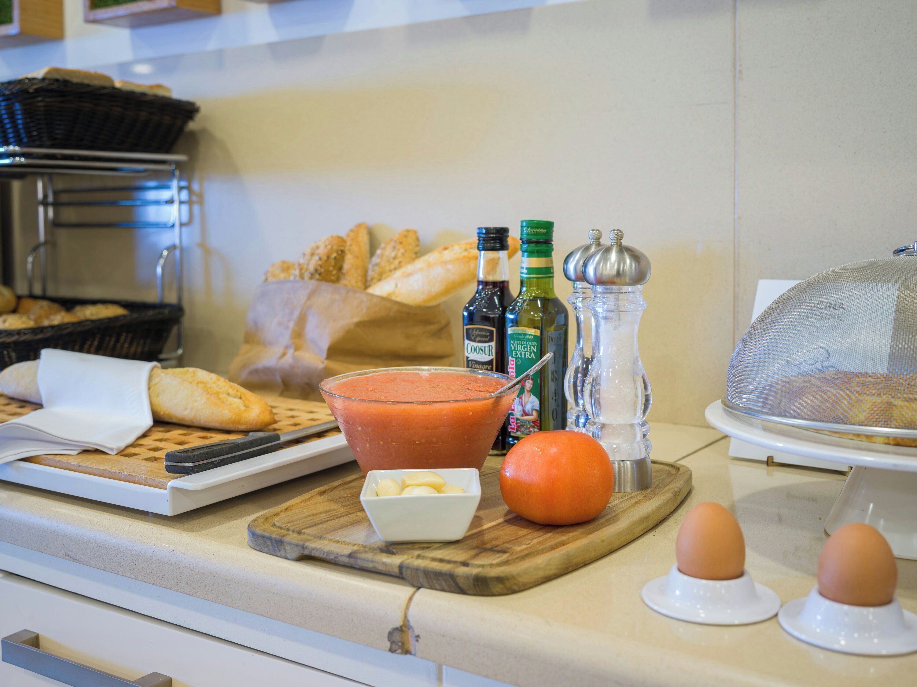 Disposición de un bufé de desayuno con pan, un tazón de sopa, salsas y huevos.