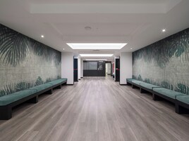 Eine moderne Lobby mit einer zentralen Sitzecke, einem Empfangstresen und einer Wand mit Muster.
