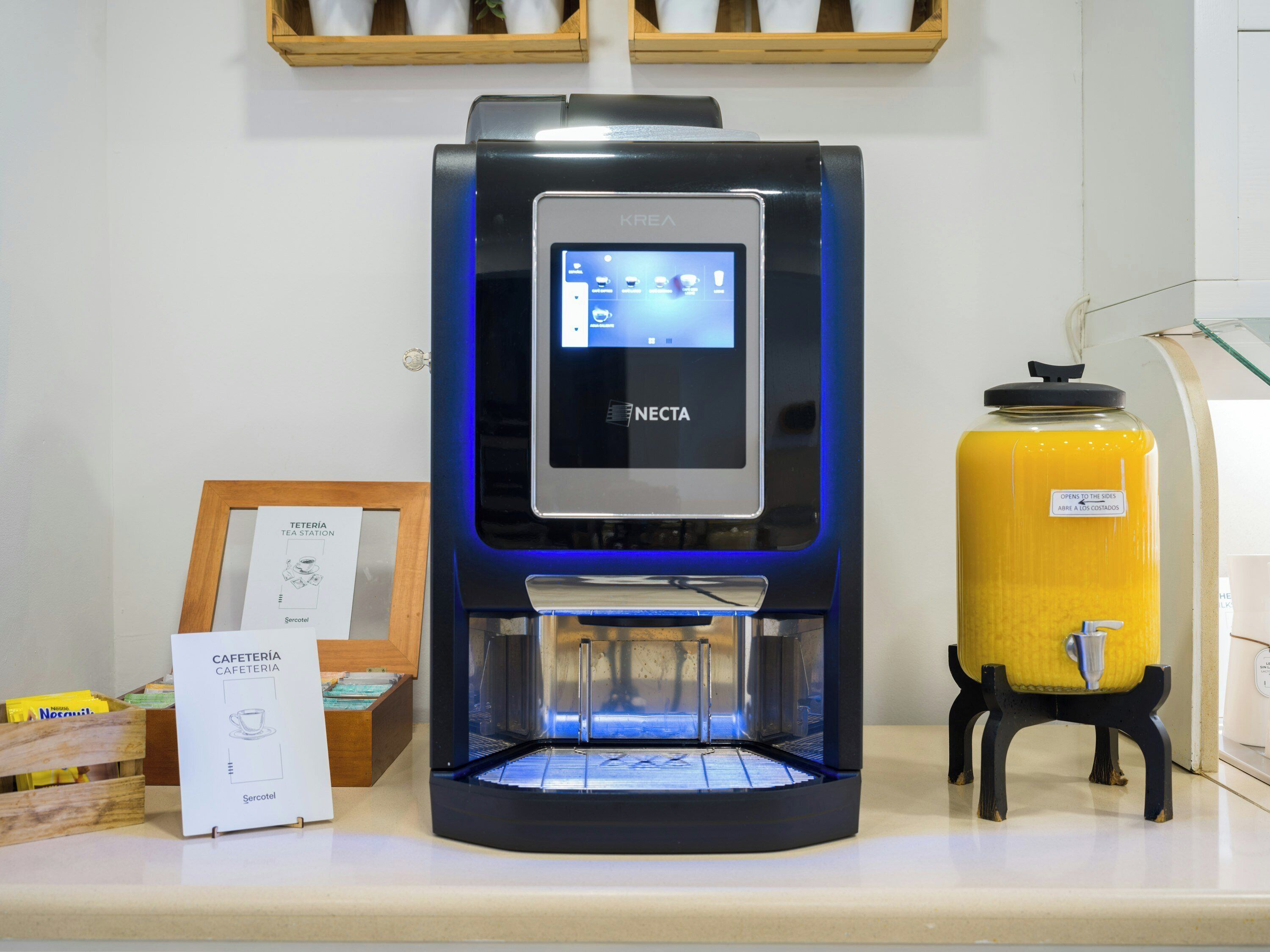Una macchina per il caffè con display digitale, un erogatore d'acqua giallo e un menu incorniciato su un bancone.