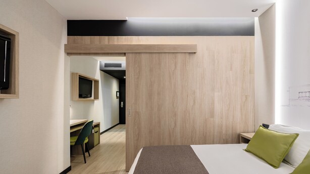 Une chambre d’hôtel moderne, équipée d’un lit, d’un bureau et d’une chaise.