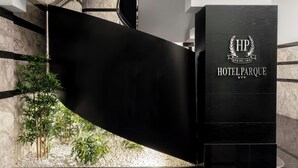 Un hall d’accueil moderne avec un comptoir noir, un mur en marbre et un petit jardin intérieur.