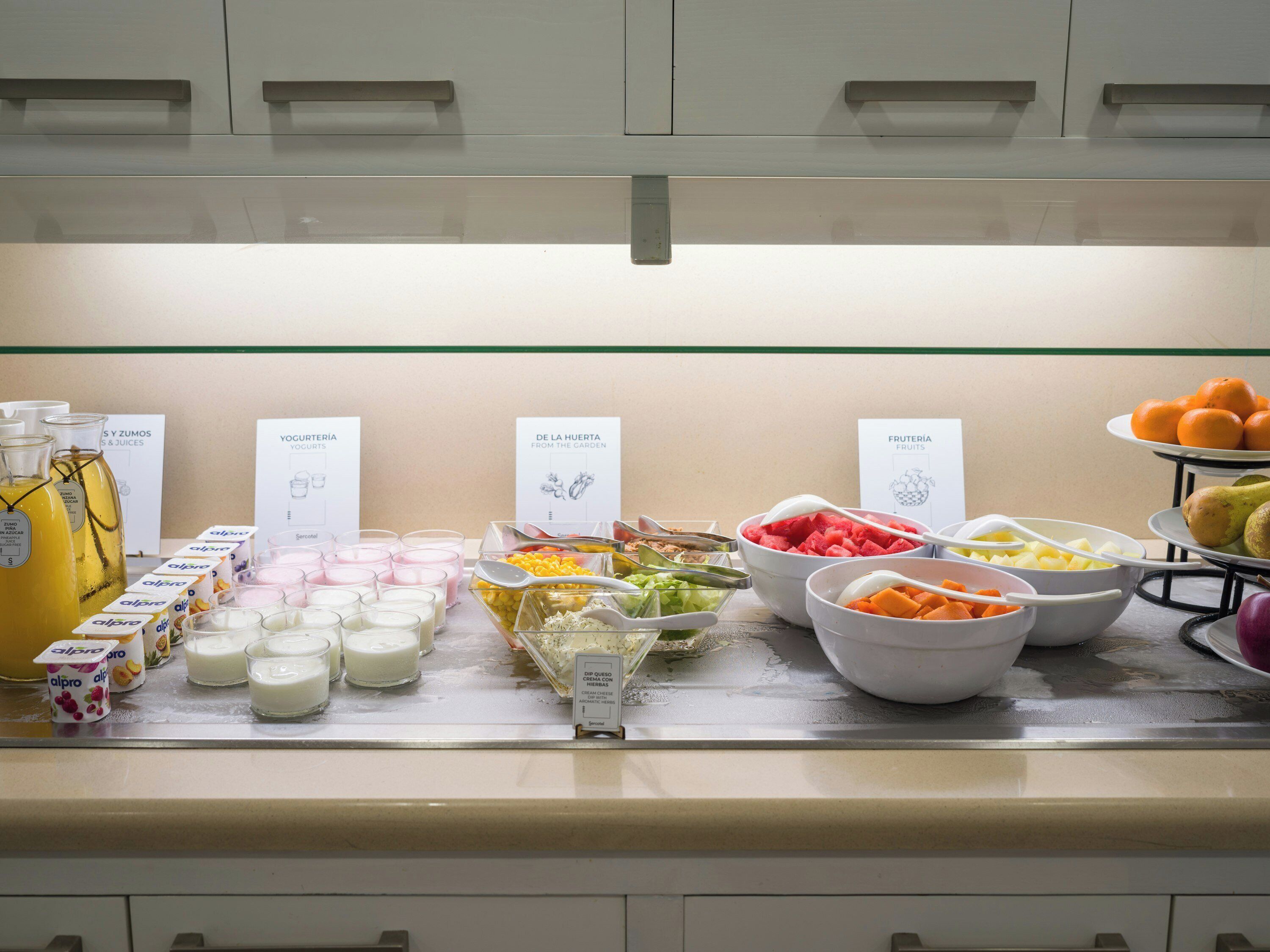 Ein reichhaltiges Buffet mit verschiedenen Speisen und Getränken, darunter Joghurt, Früchte und Dips.