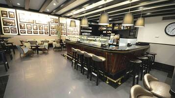 Una zona de bar con mostrador, taburetes y cuadros en la pared.