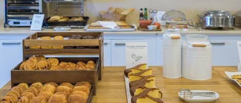 Una vitrina de pastelería con pasteles y tartas, una máquina de café y utensilios de cocina.