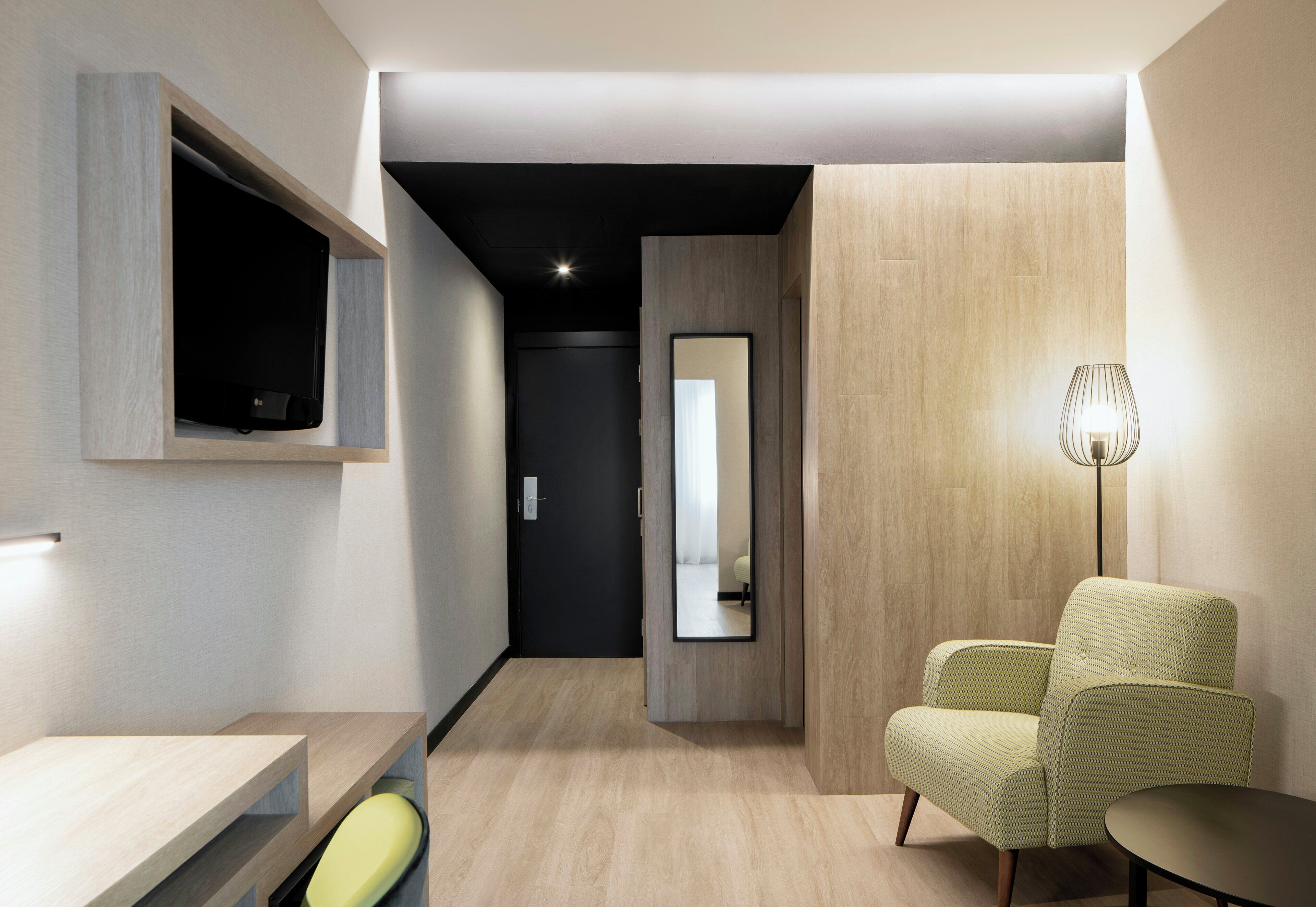 Ein modernes Zimmer mit einer Couch, einem kleinen Tisch, einem Spiegel und einer Lampe.