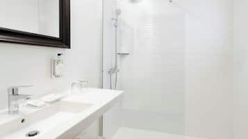 A modern bathroom with a white sink, mirror, and glass shower enclosure.