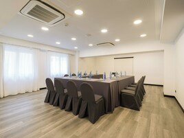 A conference room with a long table, chairs, water bottles, and a projector screen.