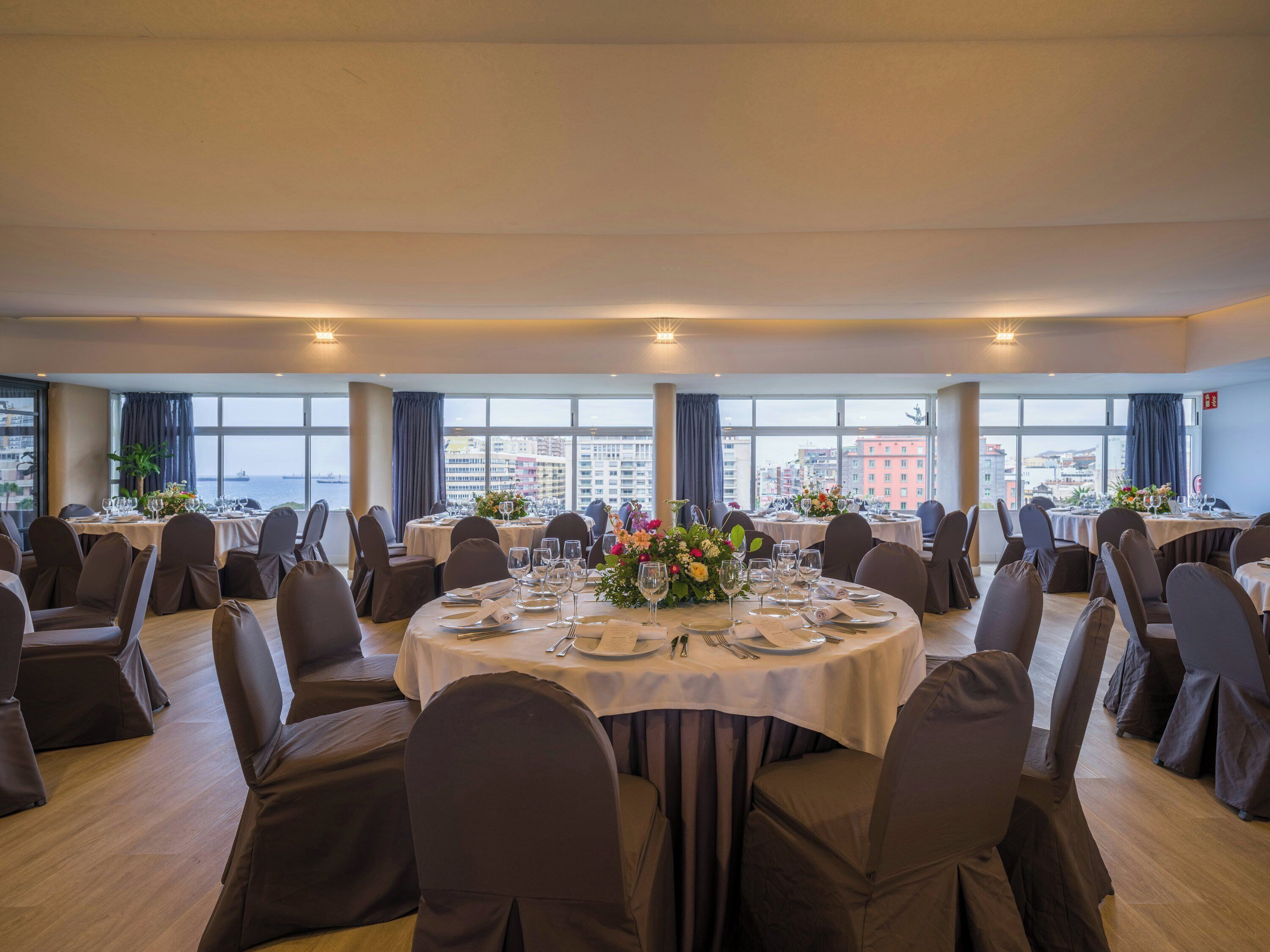 A conference room with round tables, chairs, and a city view.