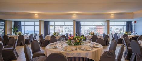 A conference room with round tables, chairs, and a city view.