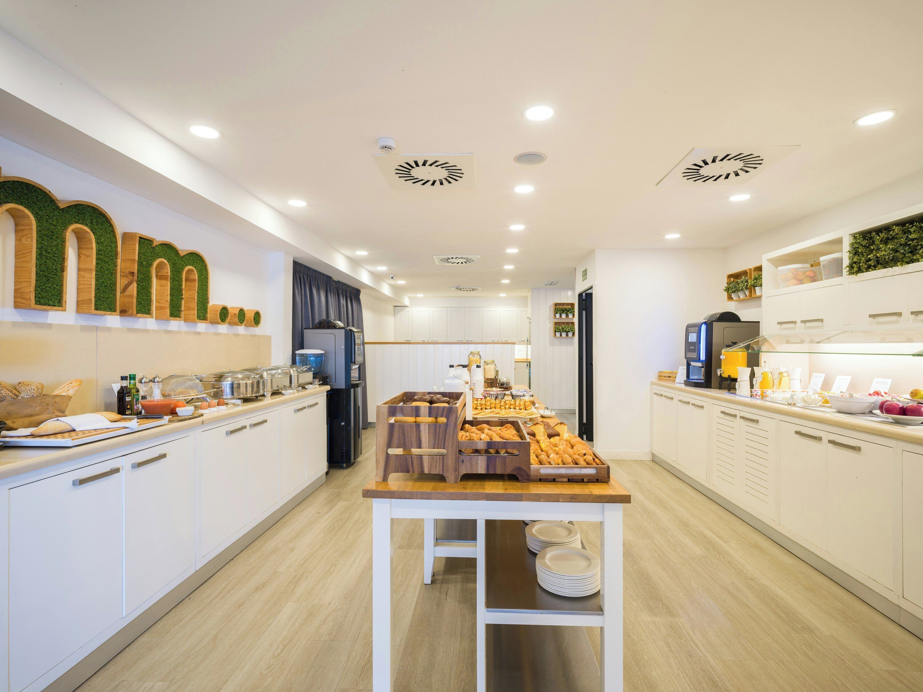Una cocina moderna con armarios blancos, una isla central con platos y una cafetera.