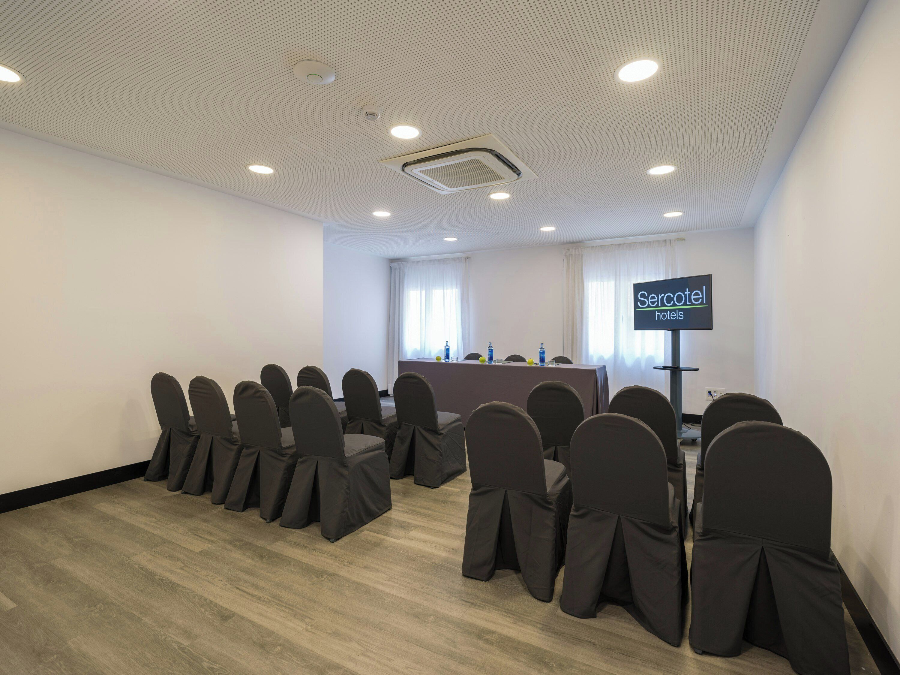 A conference room with a long table, chairs, a projector screen, and a sign indicating it's a hotel conference room.