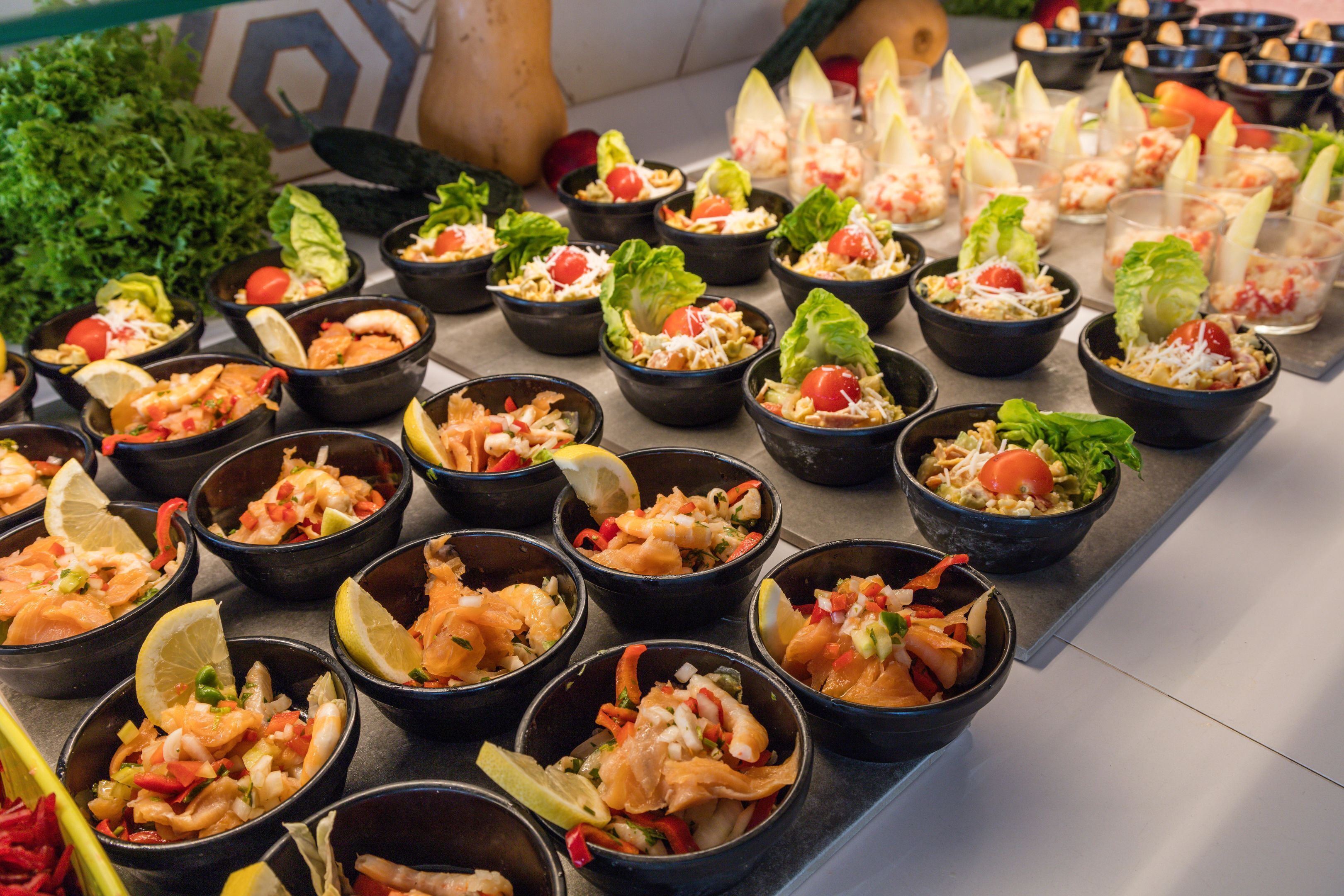 Un bufé con diversos platos de mariscos en recipientes negros, dispuestos sobre una mesa.