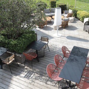 An outdoor patio area with wooden flooring, wicker chairs, and tables. - Antares & Spa Honfleur (La Riviere-Saint-Sauveur)