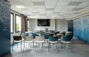 A conference room with a large table, multiple chairs, and a view of greenery outside. - Antares & Spa Honfleur (La Riviere-Saint-Sauveur)