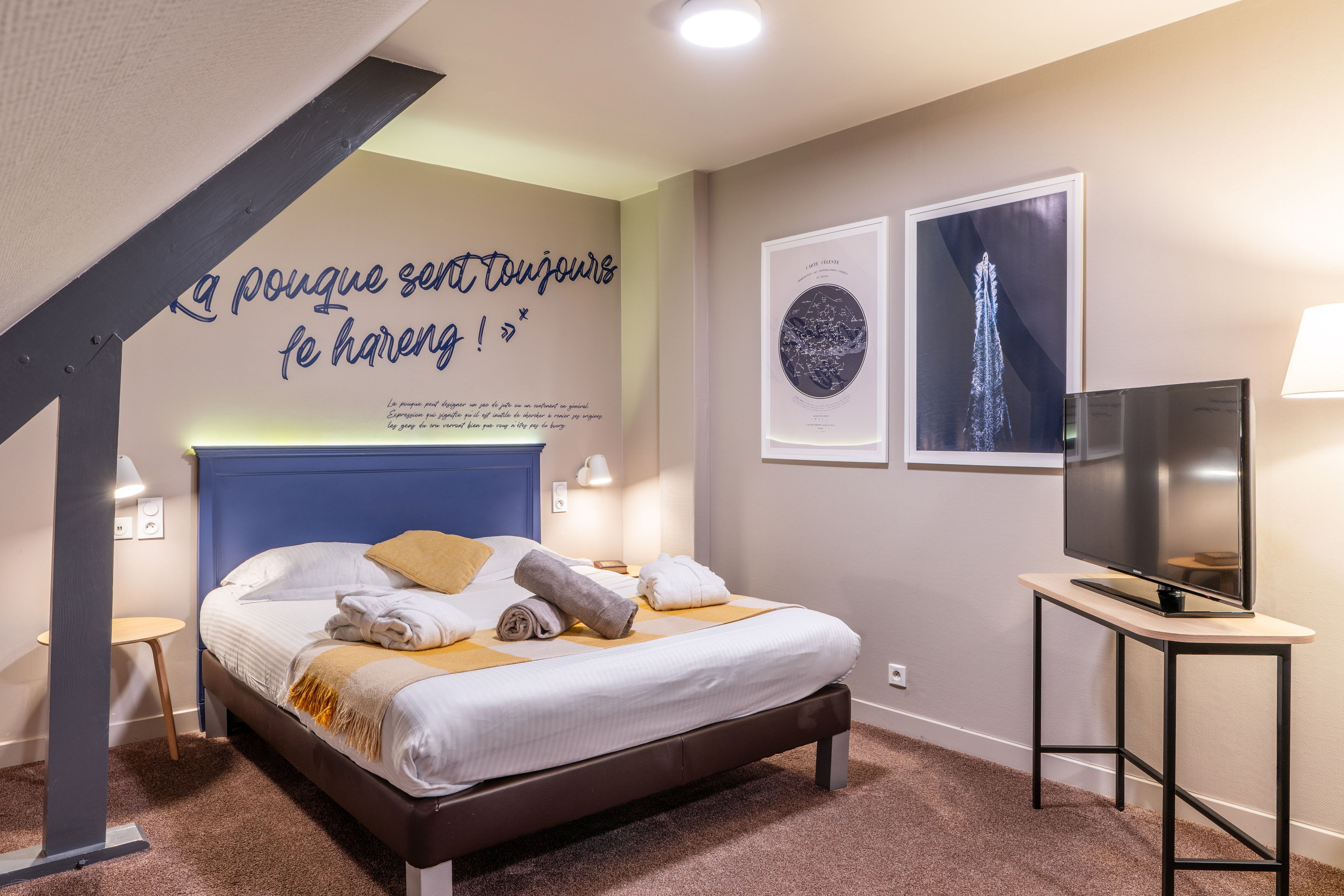 Una habitación de hotel con una cama, un televisor de pantalla plana y obras de arte en las paredes.