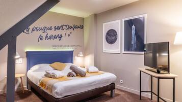 Una habitación de hotel con una cama, un televisor de pantalla plana y obras de arte en las paredes.