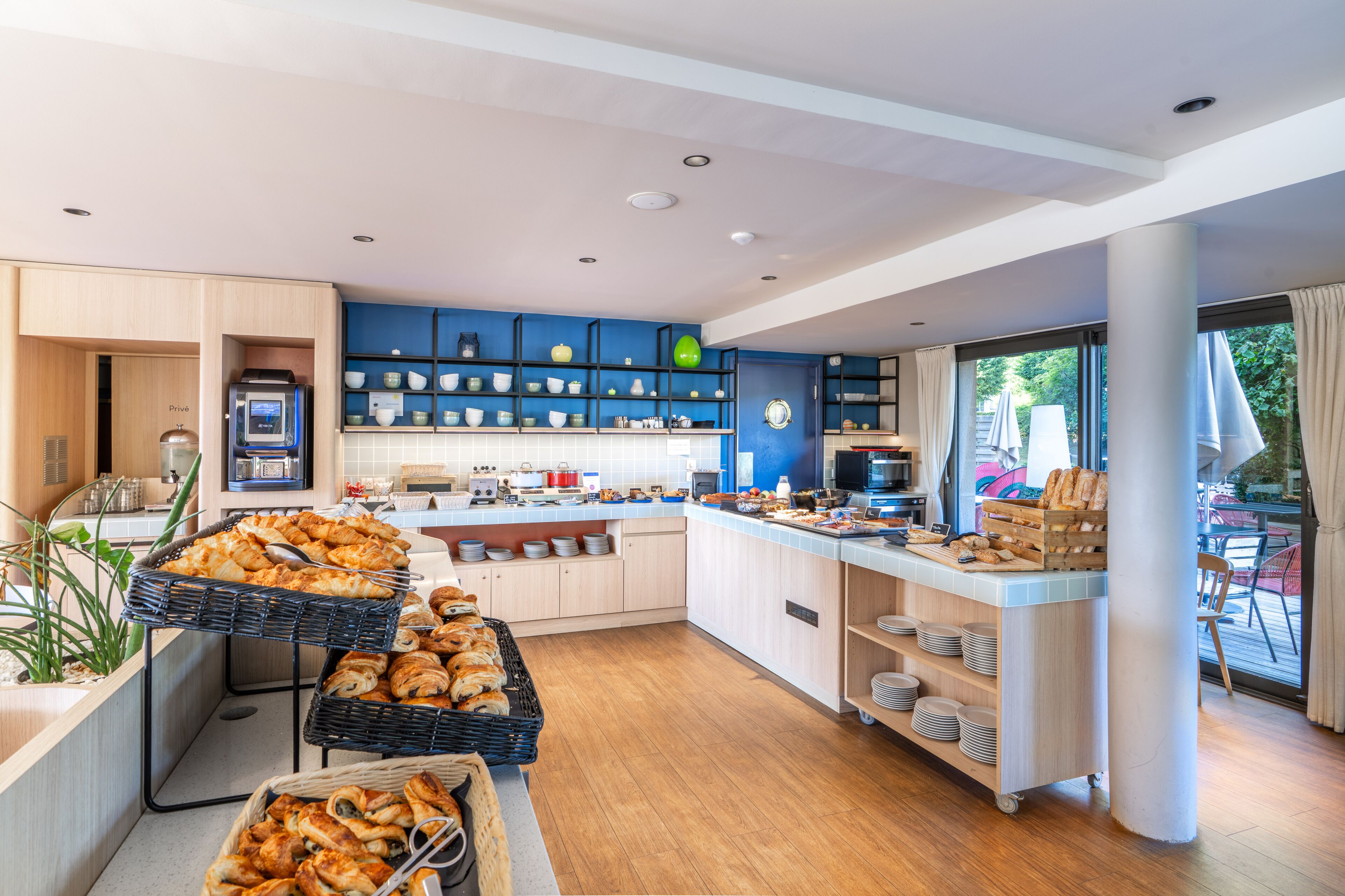 A modern kitchen with a breakfast buffet, wooden cabinets, and a view of the outdoors.