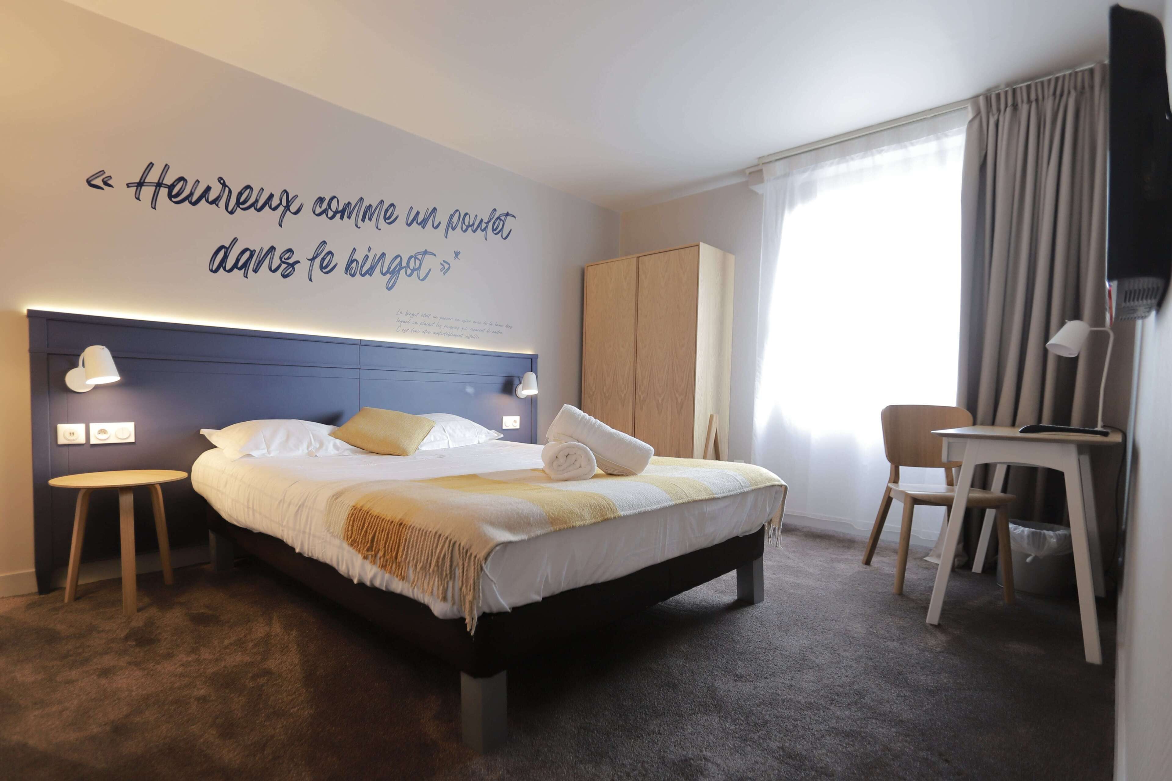 A neatly arranged hotel room with a bed, bedside lamps, a desk, and a chair.