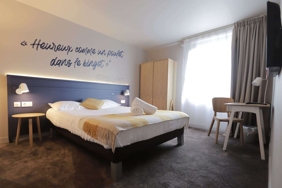 A neatly arranged hotel room with a bed, bedside lamps, a desk, and a chair.