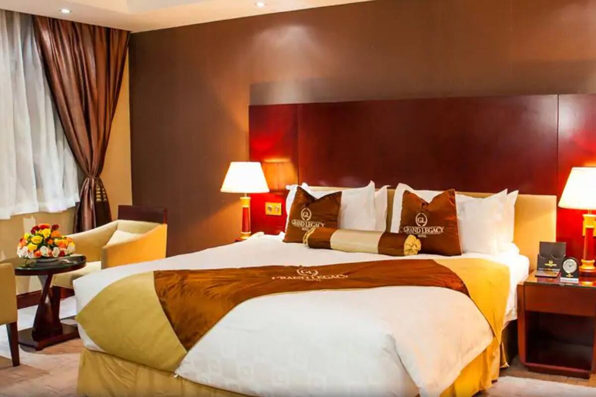 A hotel room with a large bed, two bedside tables with lamps, a chair, and a desk with a lamp.