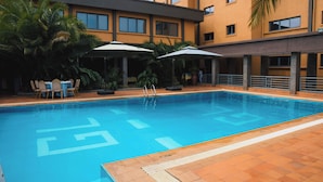 Una piscina con socorrista, sillas de descanso y sombrillas.
