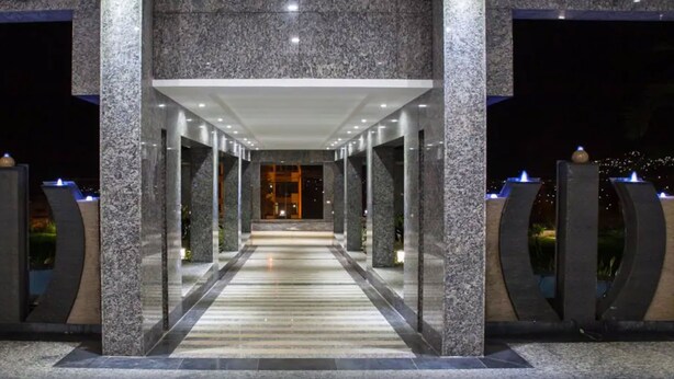 Un pasillo con piso de mármol y columnas, que conduce a la entrada de un edificio por la noche.