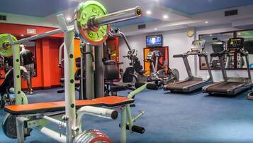 Une salle de sport équipée de divers appareils d’exercice, notamment des tapis de course, un banc de musculation et un support à squats.