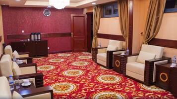 A hotel room with a red carpet, two sofas, a small table, and a cabinet.
