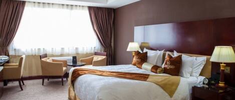 A hotel room with a large bed, two bedside tables, a desk, and a chair.