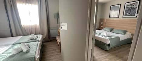 Ett hotellrum med två sängar, ett skrivbord och en stol.